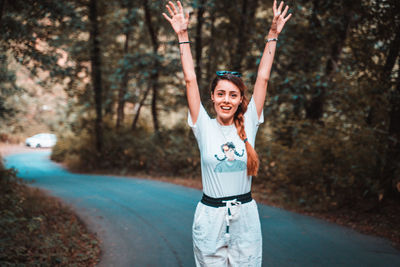 Rear view of young woman with arms raised standing on field