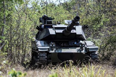 Armored tank on field against trees