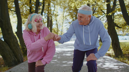 Senior man and woman bumping fists in park