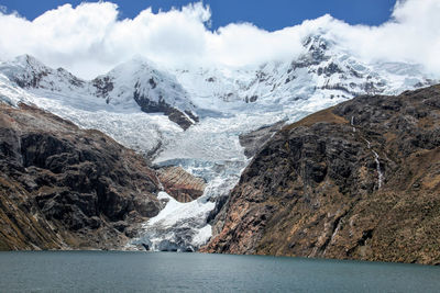 Scenic view of snowcapped mountains by sea against sky