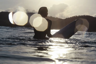 Female surfer in the ocean at sunset