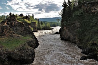 Rock formation by river against sky