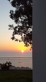 Silhouette tree by sea against sky during sunset