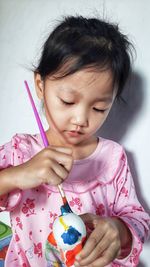 Close-up of cute girl holding pink at home
