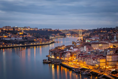 High angle view of illuminated buildings by river against sky