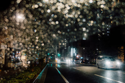 Road passing through illuminated city at night