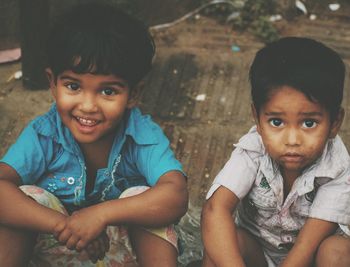 Portrait of cute brothers sitting on field