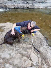 High angle view of woman with dog on rock