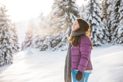 Rear view of woman standing on snow covered field