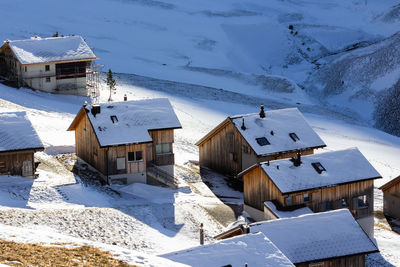 Snow covered houses by buildings against mountain