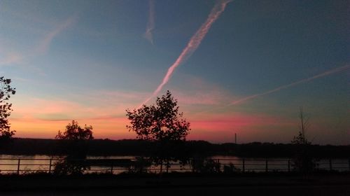 Silhouette trees by lake against sky during sunset