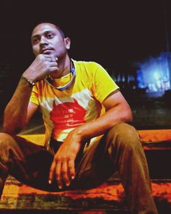 Young man looking away while sitting on seat