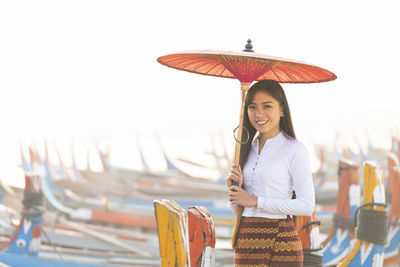 Portrait of a smiling young woman standing against sky