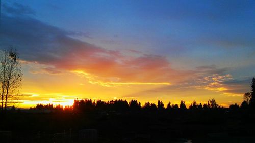 Silhouette landscape against dramatic sky during sunset