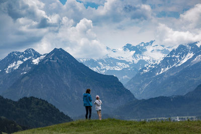 Rear view of people standing on mountain against sky