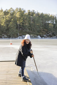 Smiling woman at lake using ice saw