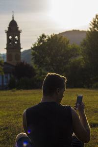 Rear view of man looking at phone in park