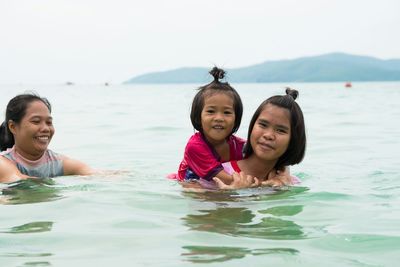 Portrait of smiling family swimming in sea against sky