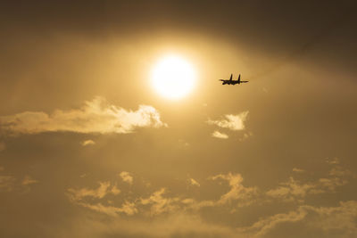 Low angle view of silhouette airplane flying against sky during sunset