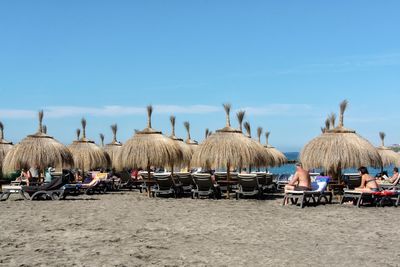 Group of people on beach against blue sky