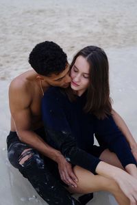 Side view of young couple sitting at beach