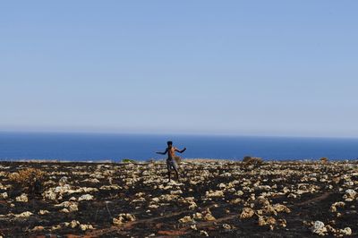 Man standing by sea against clear blue sky