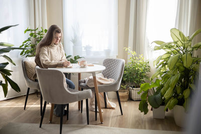 Portrait of woman sitting on table at home