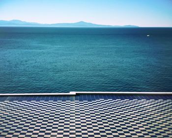 Promenade by sea against clear sky