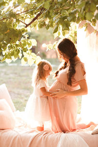 Side view of pregnant woman with daughter in garden