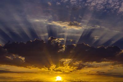 Low angle view of sun shining through clouds