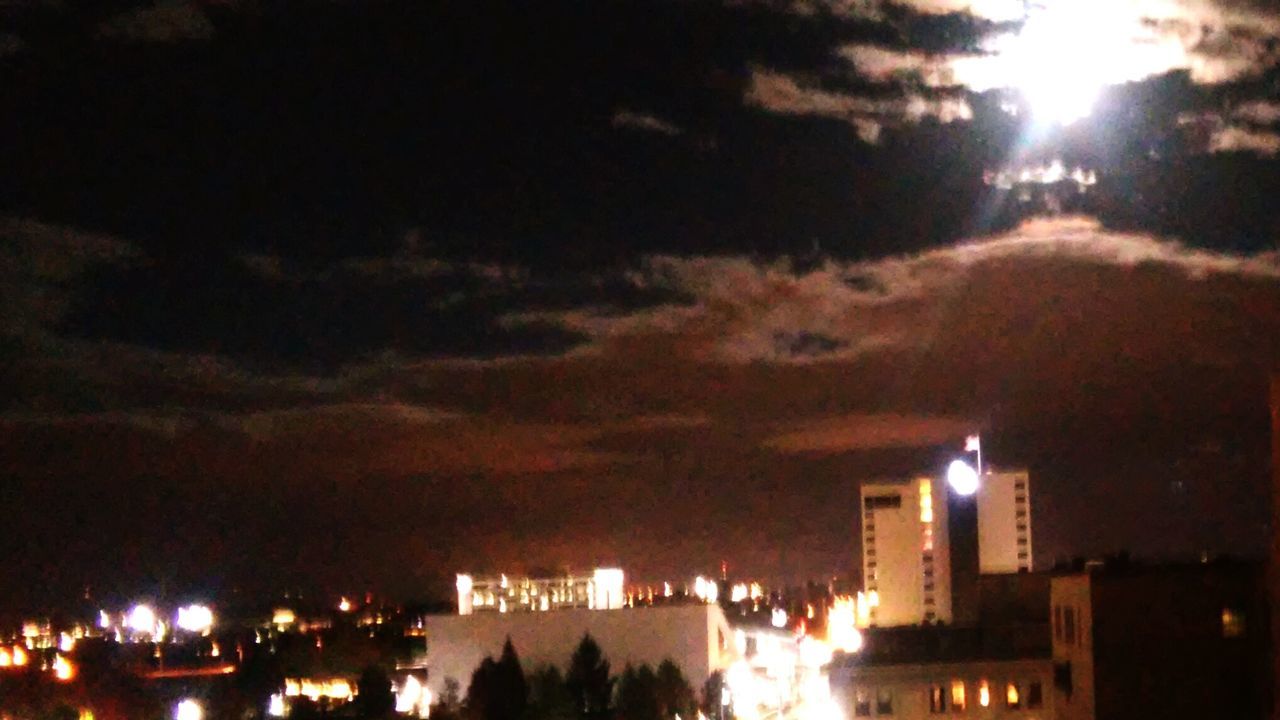 LOW ANGLE VIEW OF ILLUMINATED BUILDINGS AGAINST CLOUDY SKY