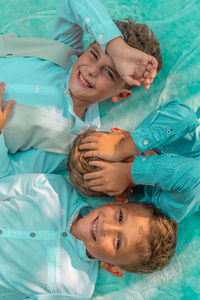 High angle view of smiling brothers lying on bed