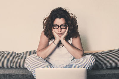 Woman using laptop while sitting on sofa at home