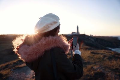 Woman using mobile phone against clear sky during sunset