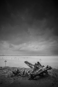 View of calm beach against cloudy sky