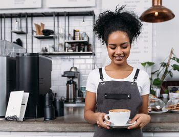 Portrait of young woman using mobile phone in cafe