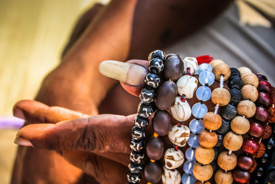 Cropped hands of man selling bead necklaces at beach