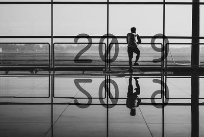 Full length of man standing on glass window at airport