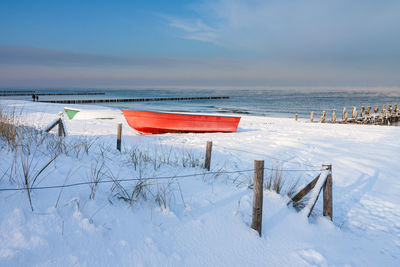 Wooden posts on beach against sky during winter