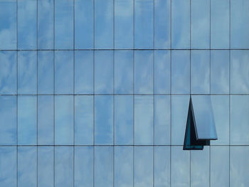 Low angle view of modern building with only one open window against blue sky