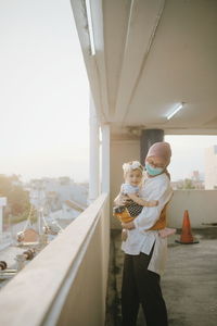 Man holding woman standing by bridge against sky in city