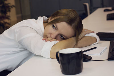 Tired woman relaxing on desk at office
