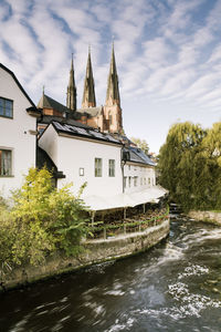 Uppsala cathedral by buildings and river fyris against sky