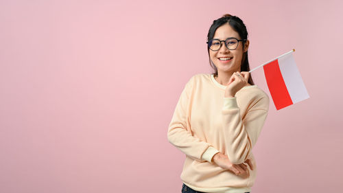 Portrait of young woman standing against yellow background