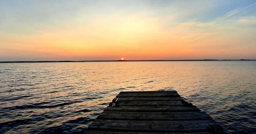 Pier over sea against sky during sunset