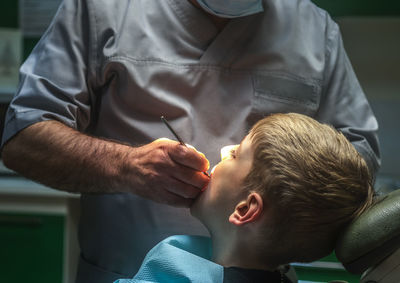 Midsection of dentist examining boy at hospital