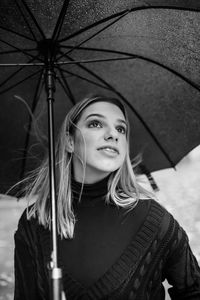 Portrait of a smiling young woman standing in rain