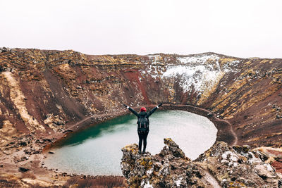 Man standing on rock by mountain against sky