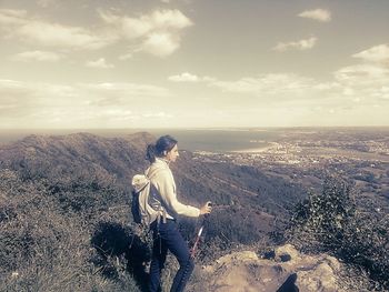 Woman on landscape against cloudy sky