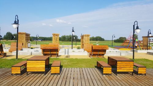 Empty benches in park against sky